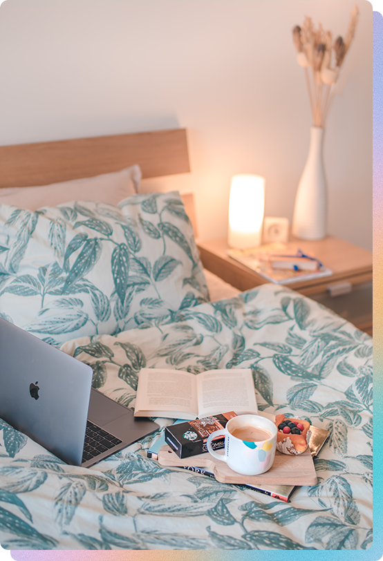 Laptop computer on a colorful patterned bedspread in a relaxing home environment.